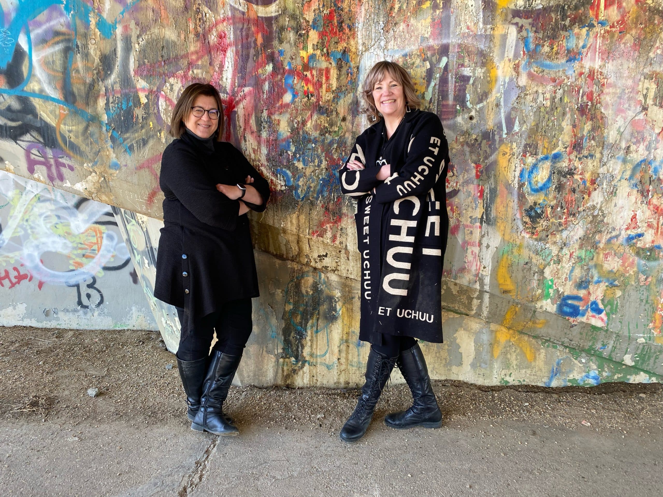 Shan and Rita full body, leaning against a graffiti wall