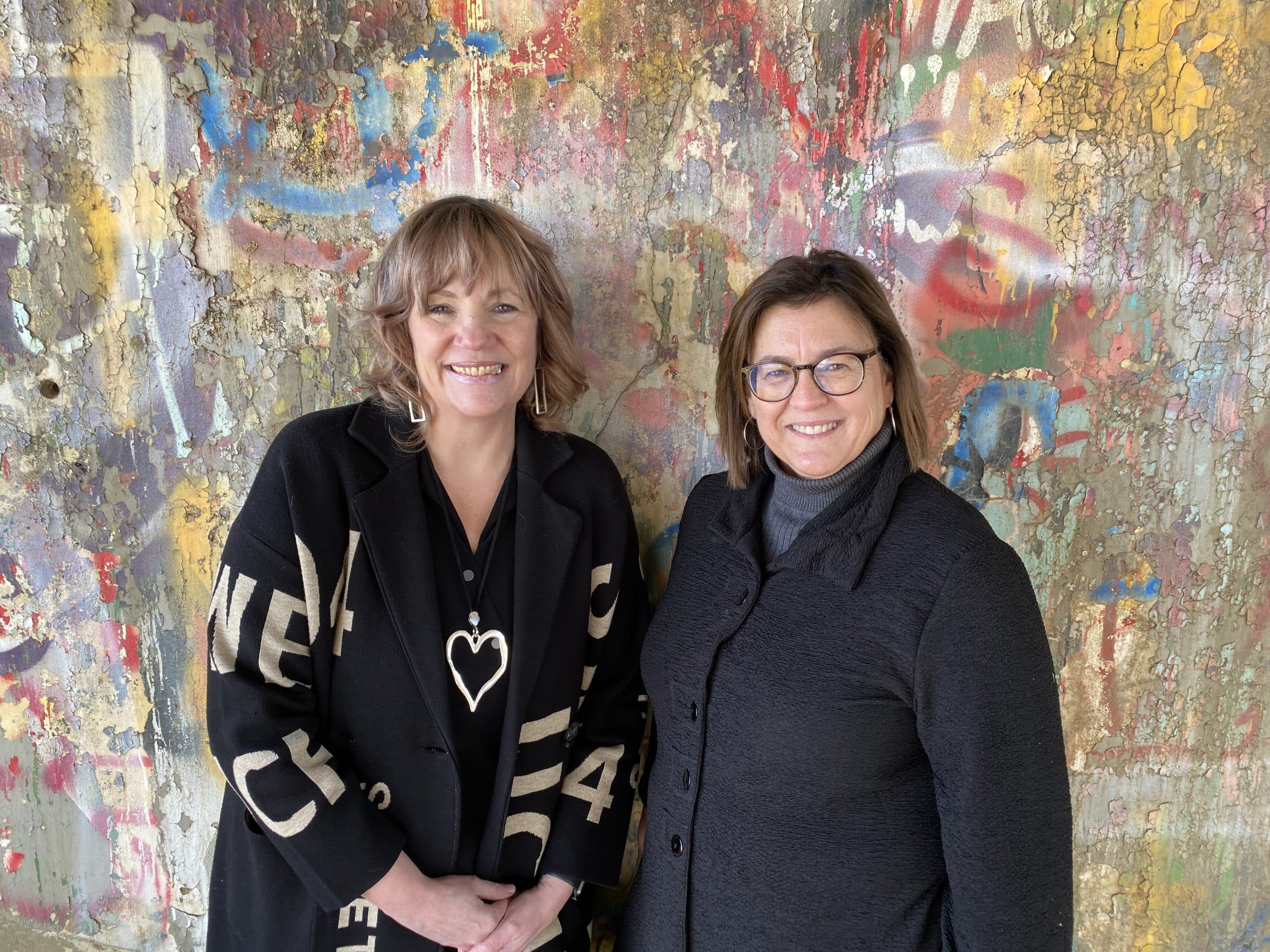 Shan and Rita standing together by a colourful mural