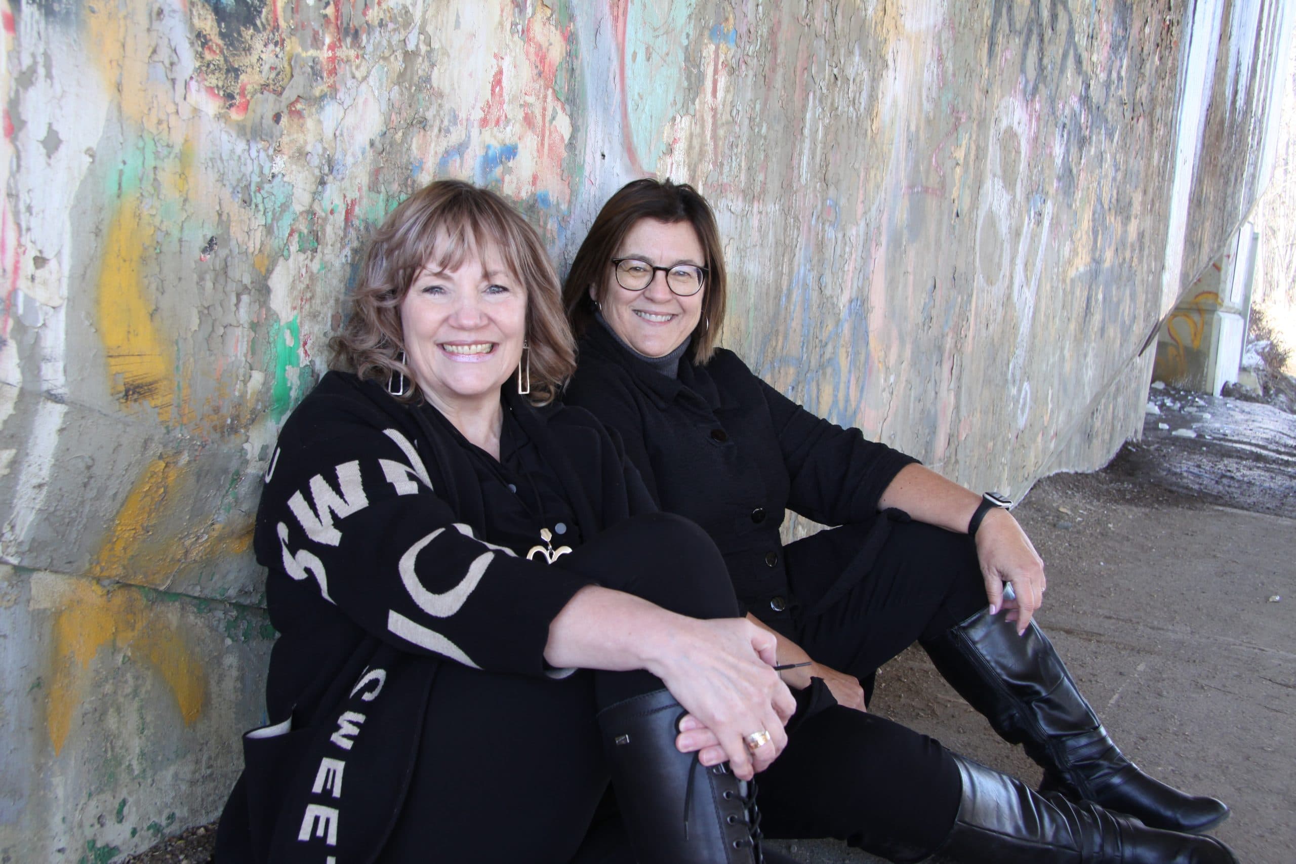 Shan Jorgenson-Adam and Dr. Rita Marler sitting together by a graffiti wall